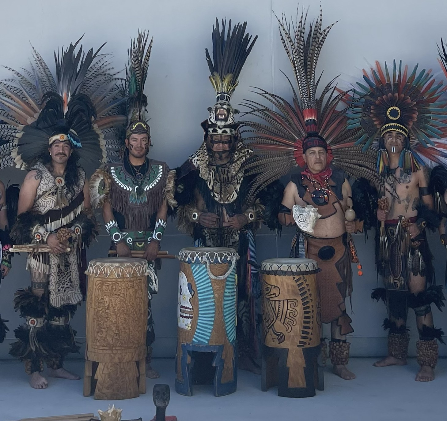 Five Aztec drummers in full feathered regalia with ceremonial drums